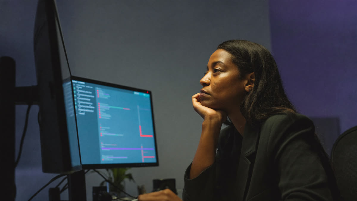 A security engineer reviews an AI agent activity log on a monitor late in the evening