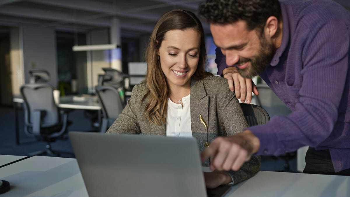 An operations manager builds a workflow agent on her laptop while a colleague points at the screen